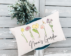 Personalized Mother's Day pillow featuring birth month flowers of each grandchild. The pillow is decorated with colorful floral designs representing the birth month flowers and customized with the names of each grandchild.